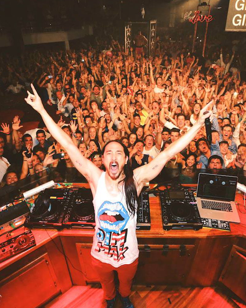 Steve Aoki in his typical pose atop the DJ booth