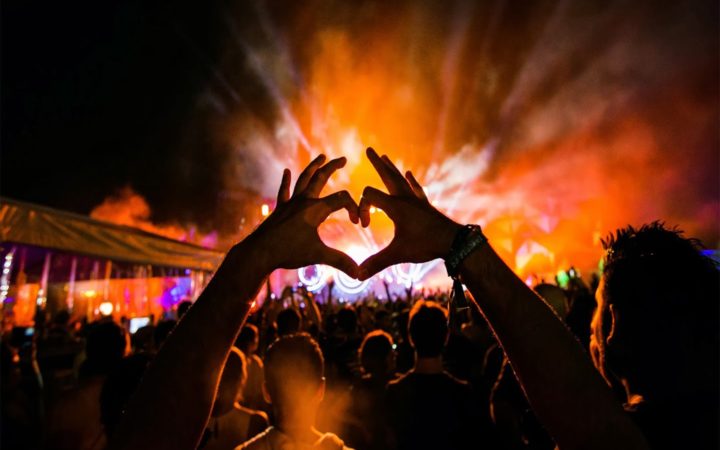 two hands coming together to form a heart at an EDM festival