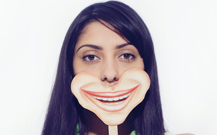 Woman in 20's Holding Smile Mask in Front of Face