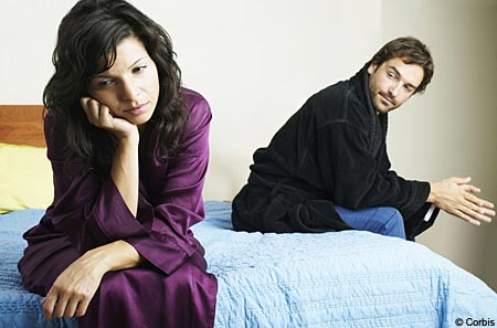 an unhappy male and female in a relationship on a bed