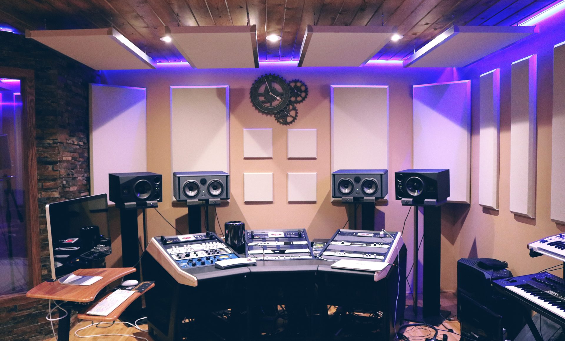 A recording studio control room with wall treatments and purple overhead lighting