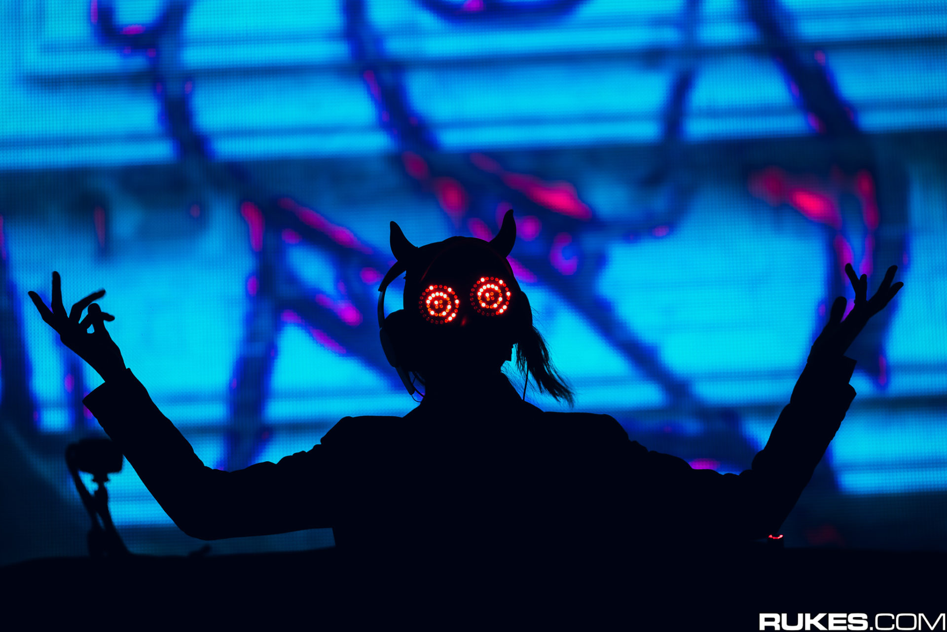 Rezz on stage with her hands up wearing her glasses