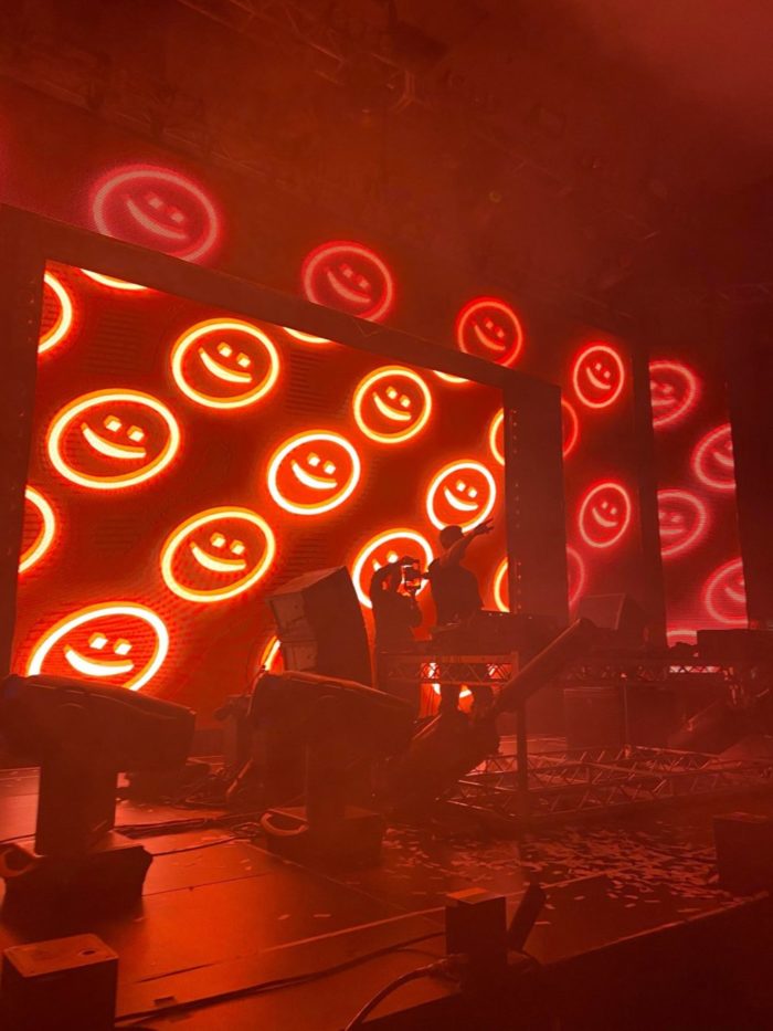 Shot of Darren Styles performing in Vancouver BC indoors with red lights and red smiley face visuals.