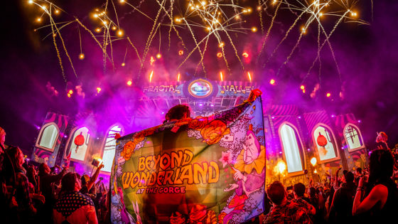Person holds beyond wonderland flag in front of stage.