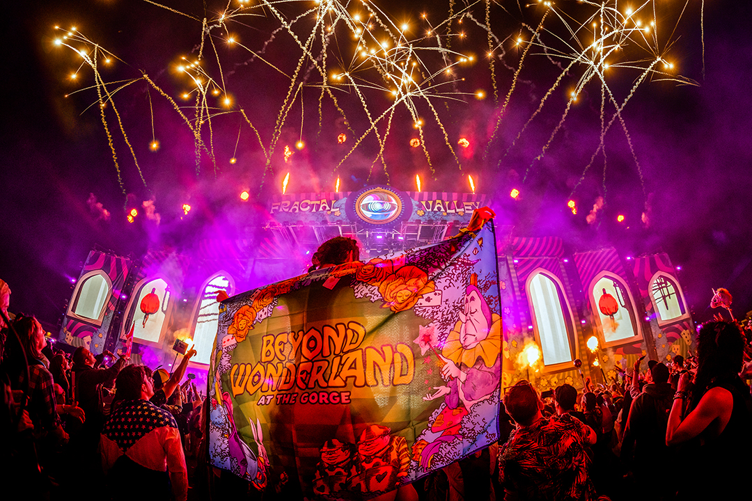 Person holds beyond wonderland flag in front of stage.
