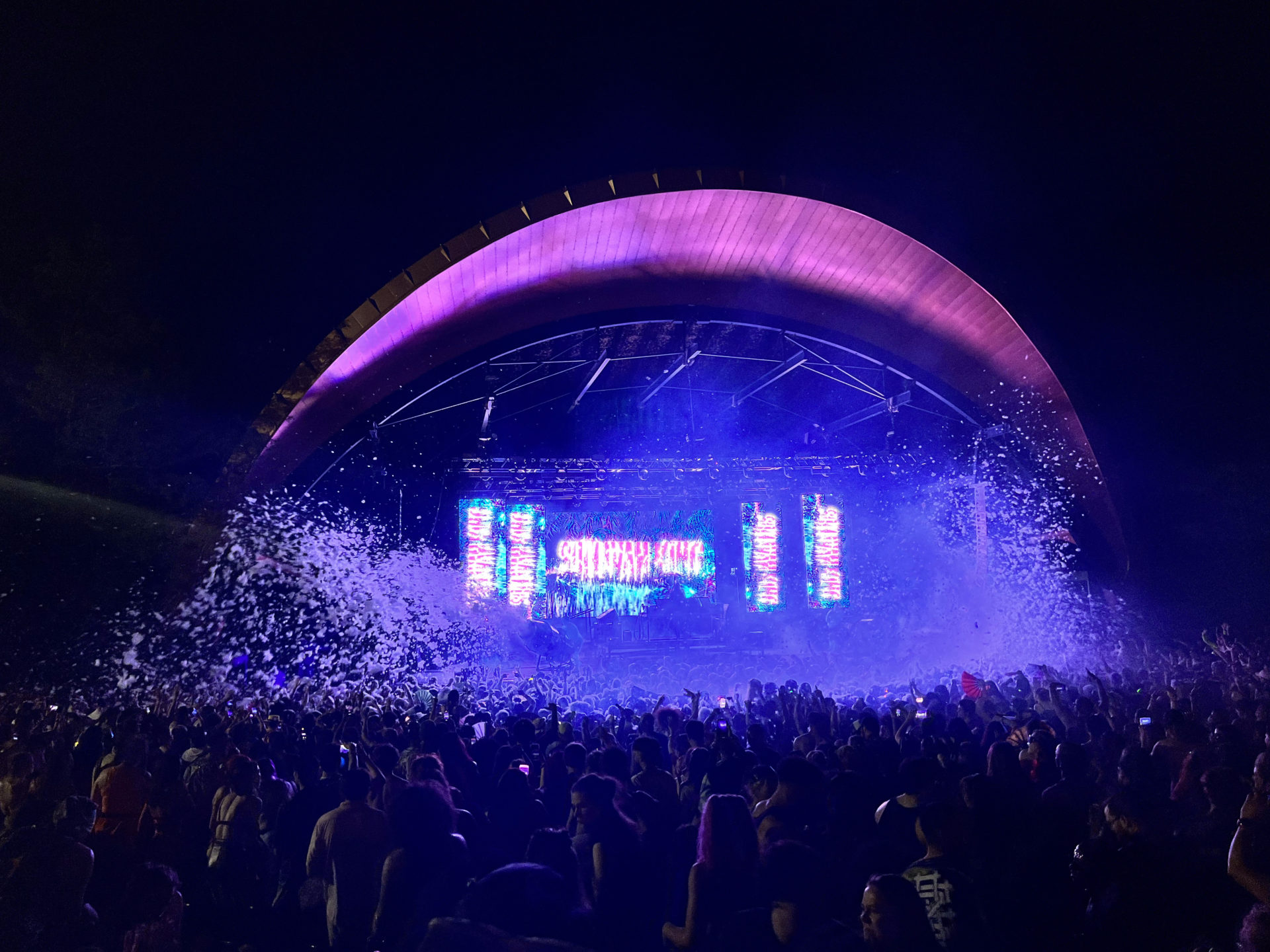 Sullivan King performing with blue background and waves of foam falling on the crowd