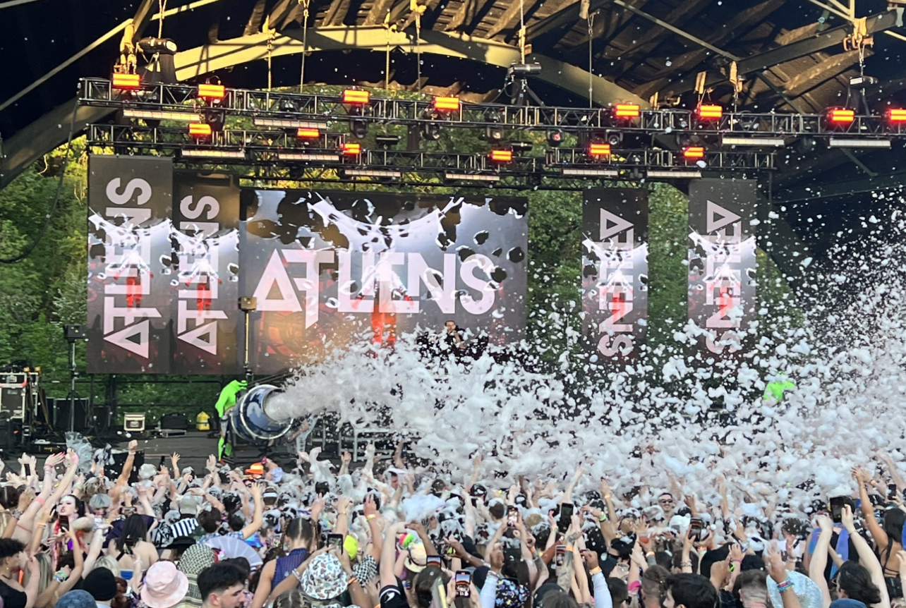 ATLiens performing while men in green suits spray the audience with foam cannons