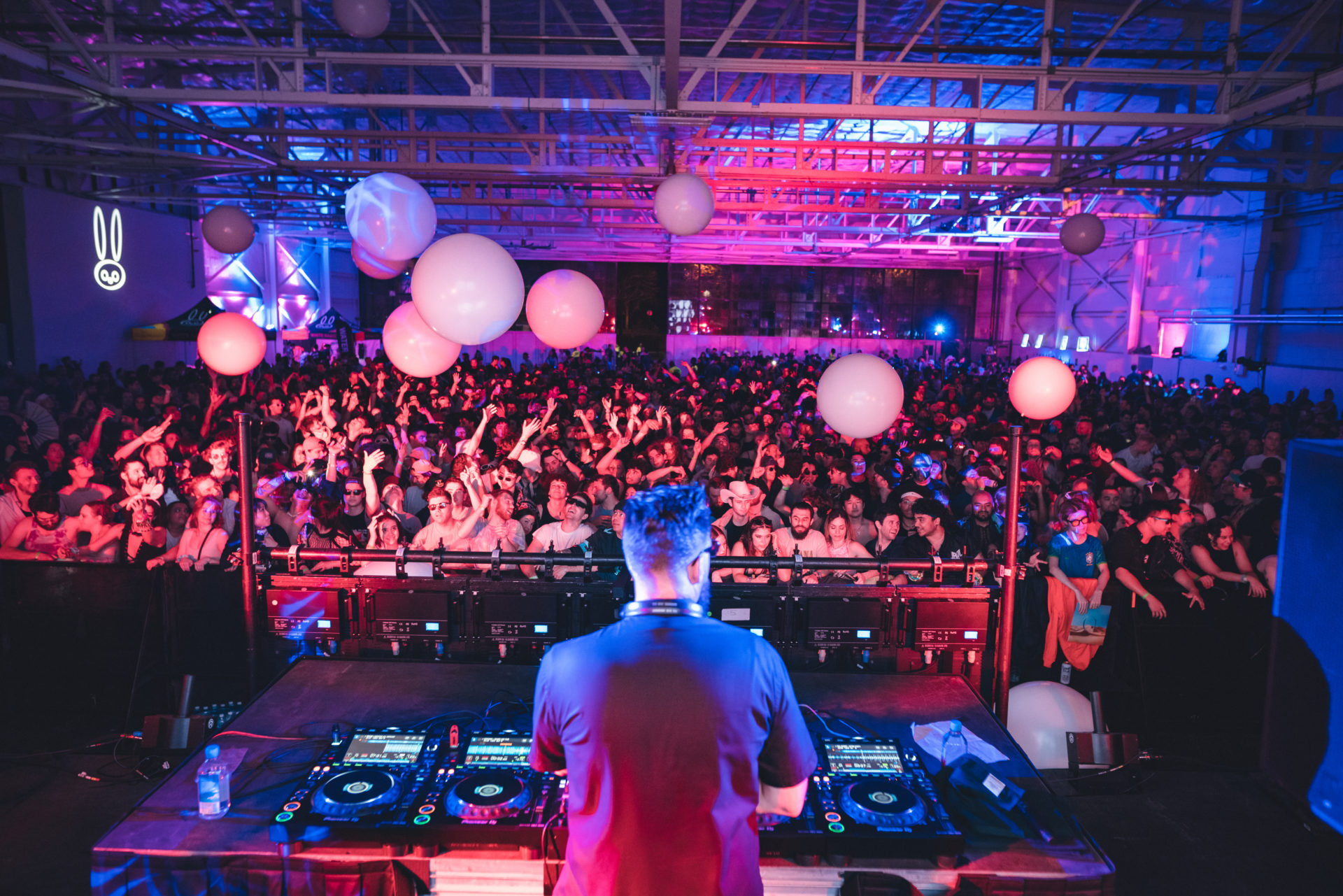Tchami perfroming in a large hangar with white beach balls in the crowd
