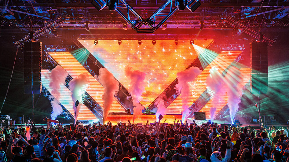 main stage shot with orange lights and pink smoke/green lasers