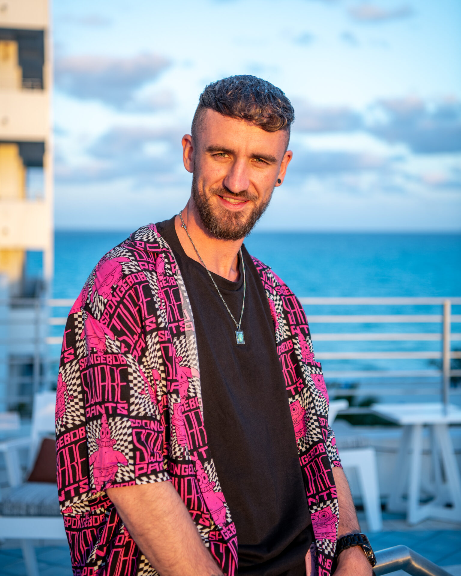 Billy Gillies wearing a red flannel and standing in front of water.