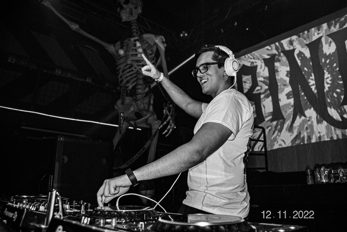 Bindy performing with giant skeleton behind him in black and white