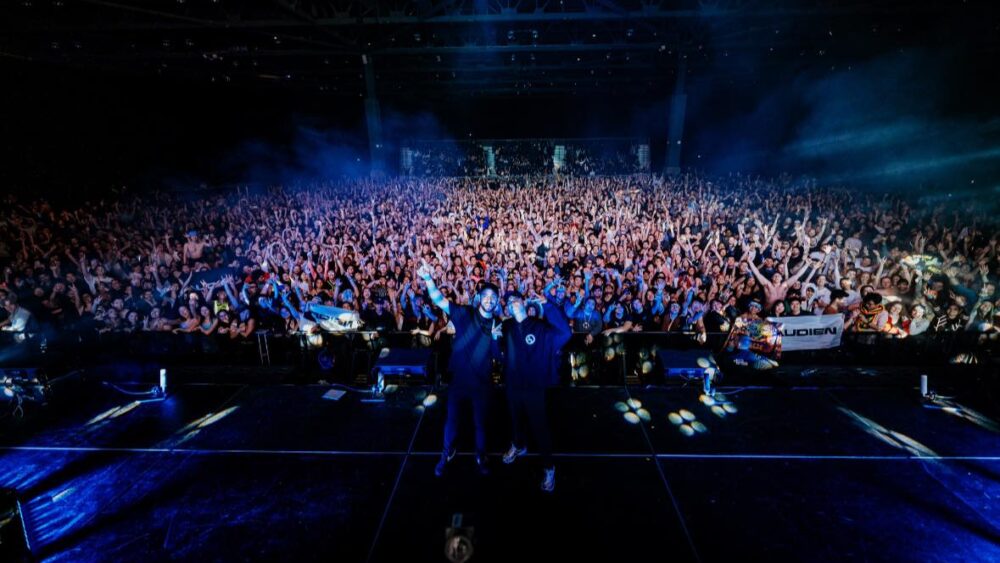 pic of Audien and Jason Ross standing on stage with crowd behind posing for picture from Seattle show 2024.