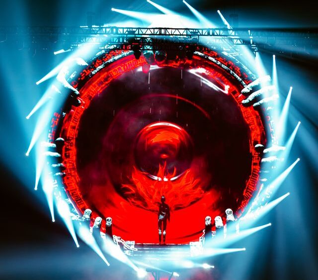 A digital picture of a blue portal swirling around a red center, with Rezz standing inside.