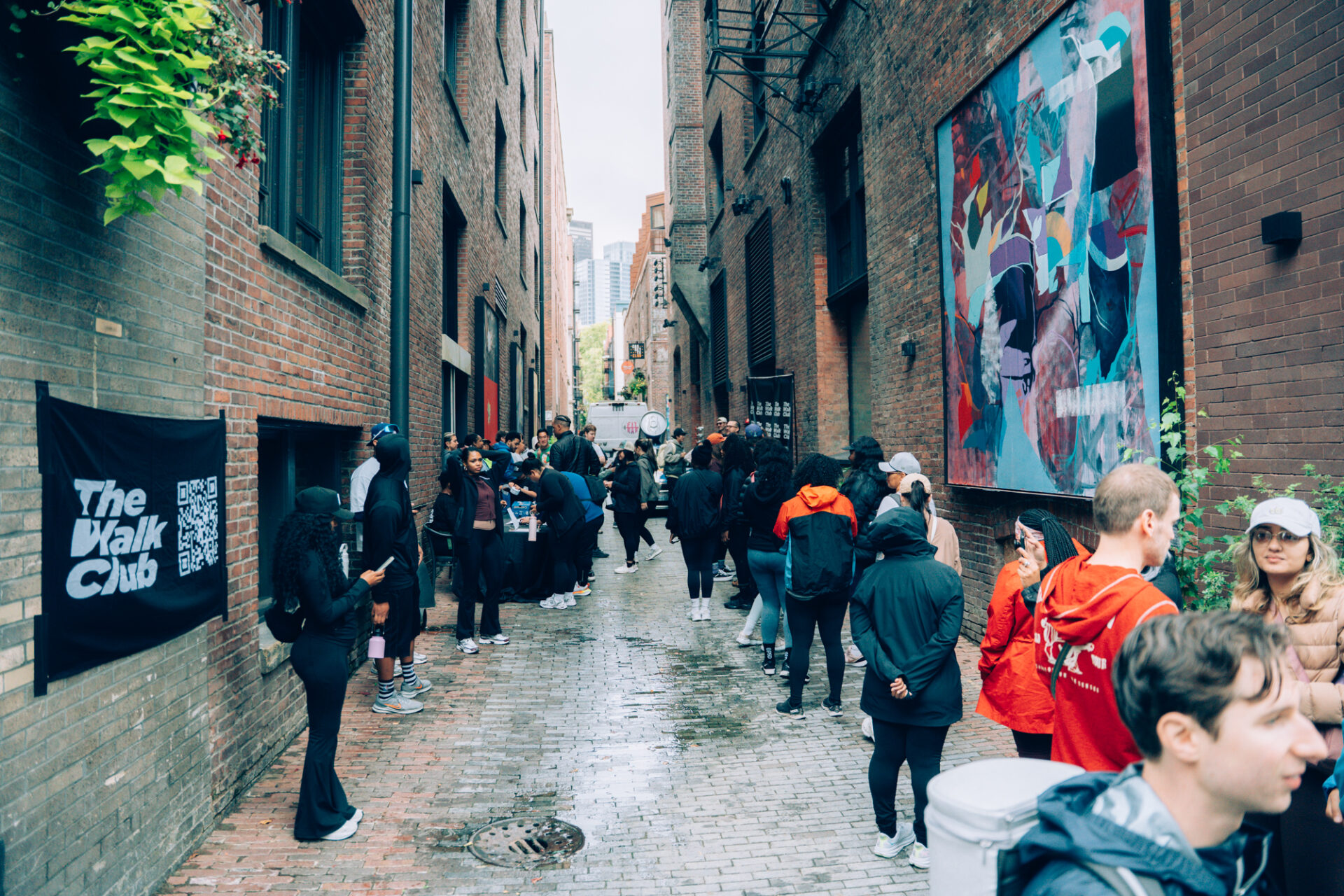 Walk Club participants walking through a Seattle alley with art murals and TWC banners