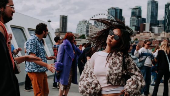 woman in sunglasses dancing to electronic music in front of the Seattle ferris wheel