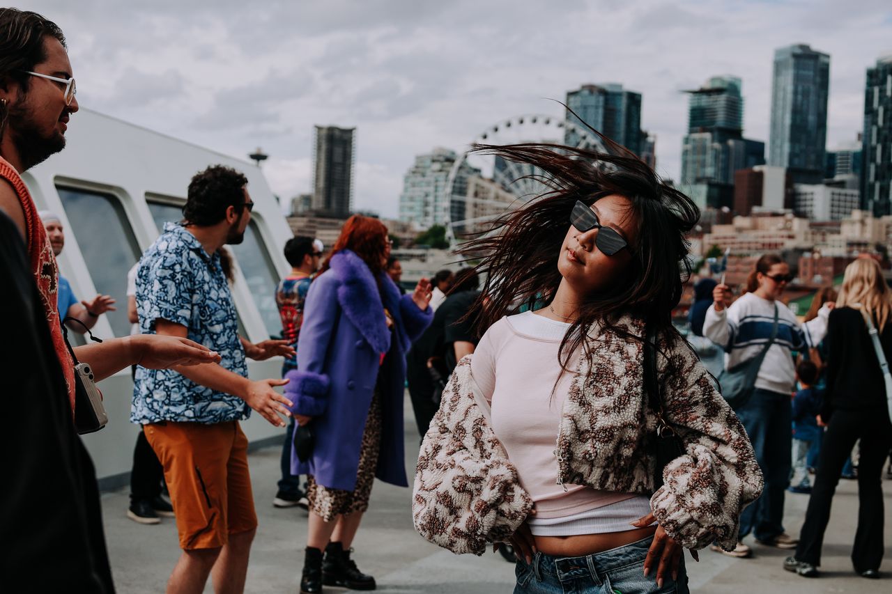 woman in sunglasses dancing to electronic music in front of the Seattle ferris wheel