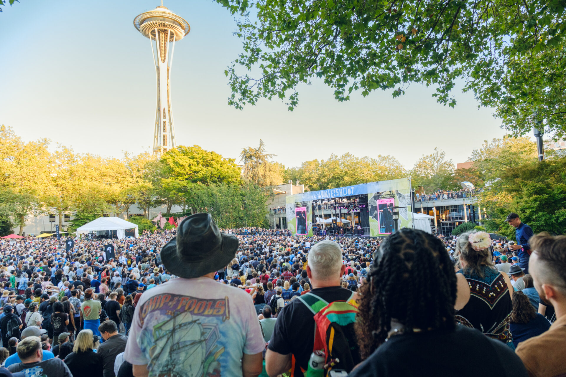 Looking at the Fisher Stage over the crowd with the sunny Space Needle in the background at Bumbershoot 2026